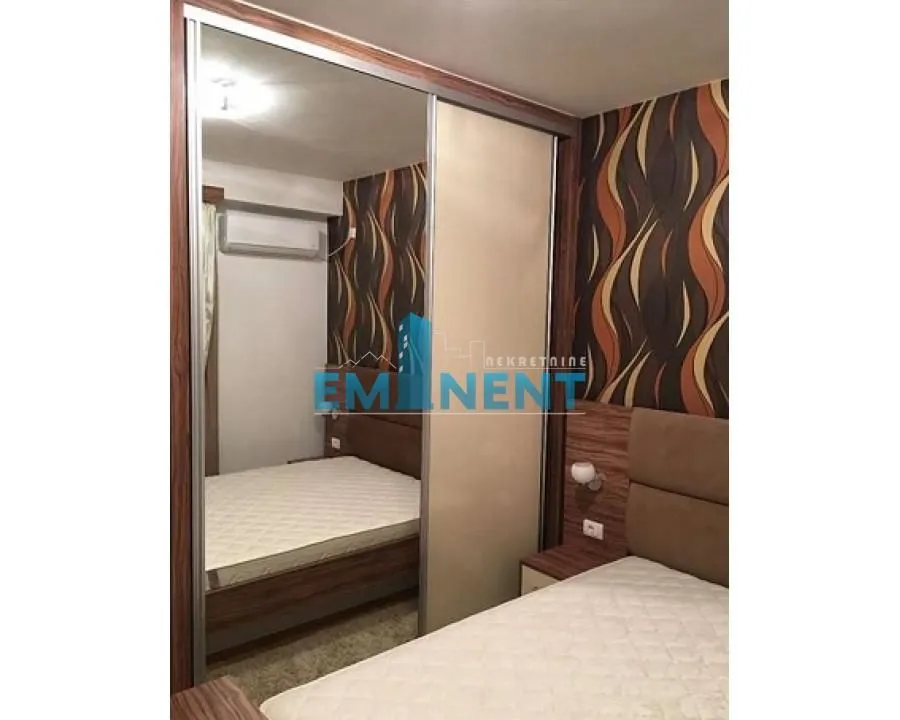 Furnished bedroom with a large mirrored wardrobe.