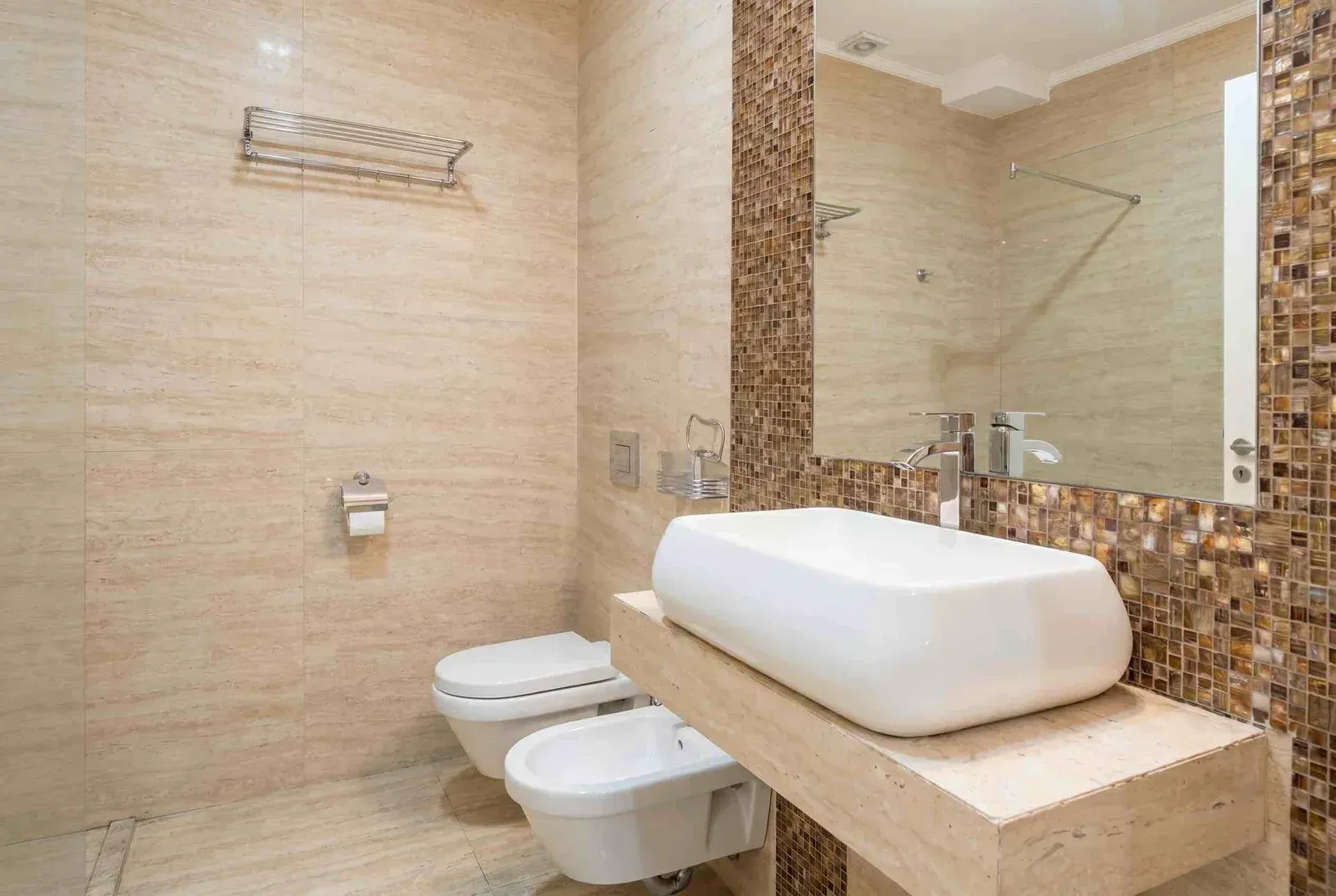 Modern bathroom tiled with ceramic tiles featuring a sink, toilet, and bidet.