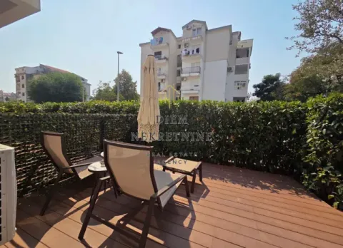 Terrace with wooden decking, sun loungers, and a view of the building and greenery. - image 12