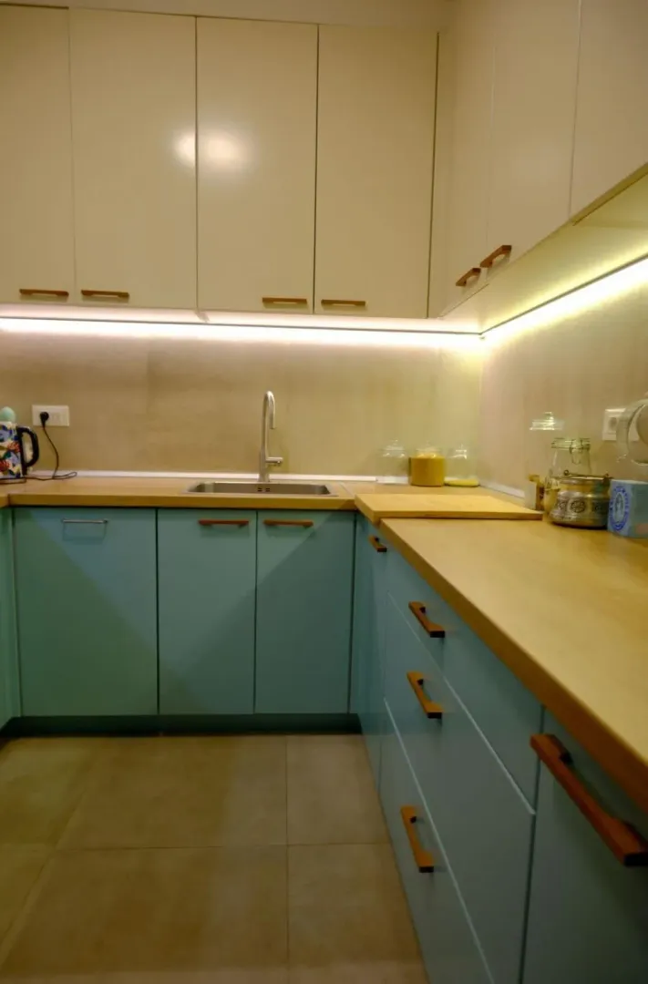 Kitchen with turquoise cabinets, wooden countertop, and built-in lighting.