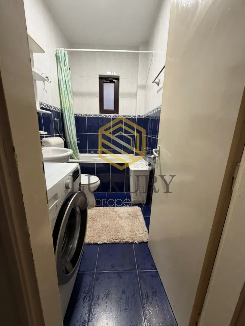 Smaller bathroom with blue tiles, bathtub, and washing machine.