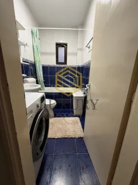 Smaller bathroom with blue tiles, bathtub, and washing machine. - image 5