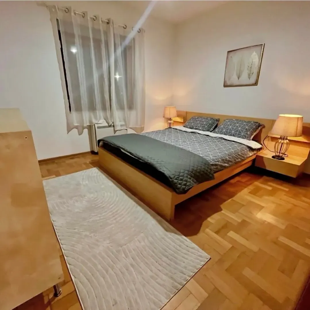 Furnished bedroom with a double bed and parquet flooring.
