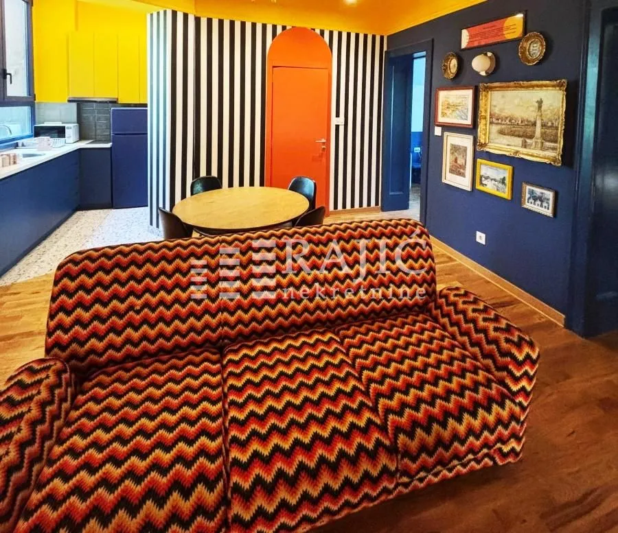 Living room with a patterned sofa and a dining table in the background.