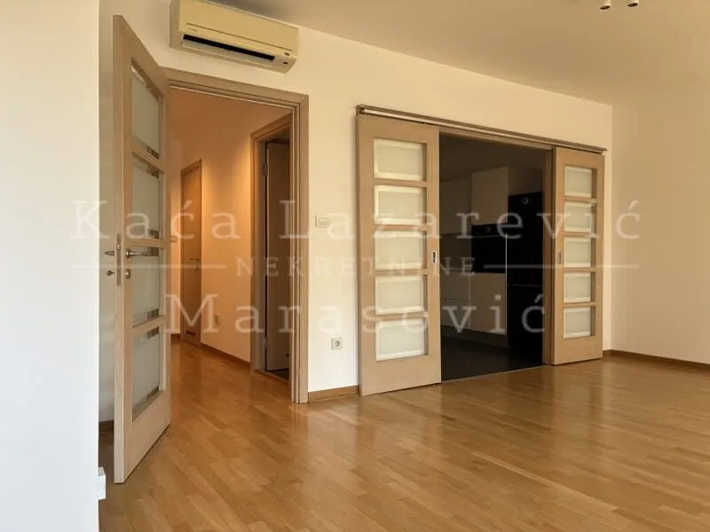 Living room with wooden flooring and sliding doors leading to another room.