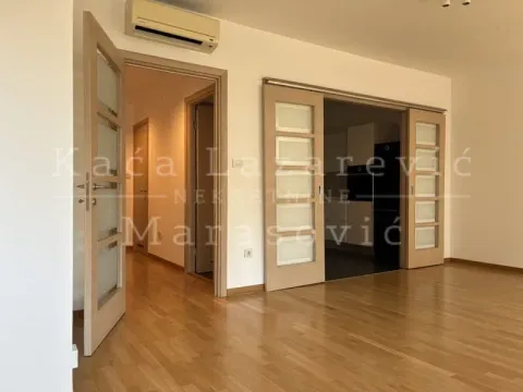 Living room with wooden flooring and sliding doors leading to another room. - image 6