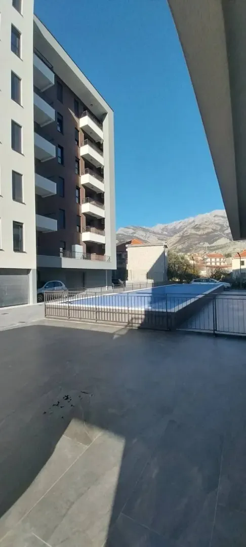 Eksterijer stambene zgrade sa bazenom i pogledom na planine.