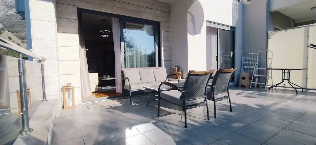 Prostrana terasa sa udobnim baštenskim namještajem ispred ulaza u apartman.
