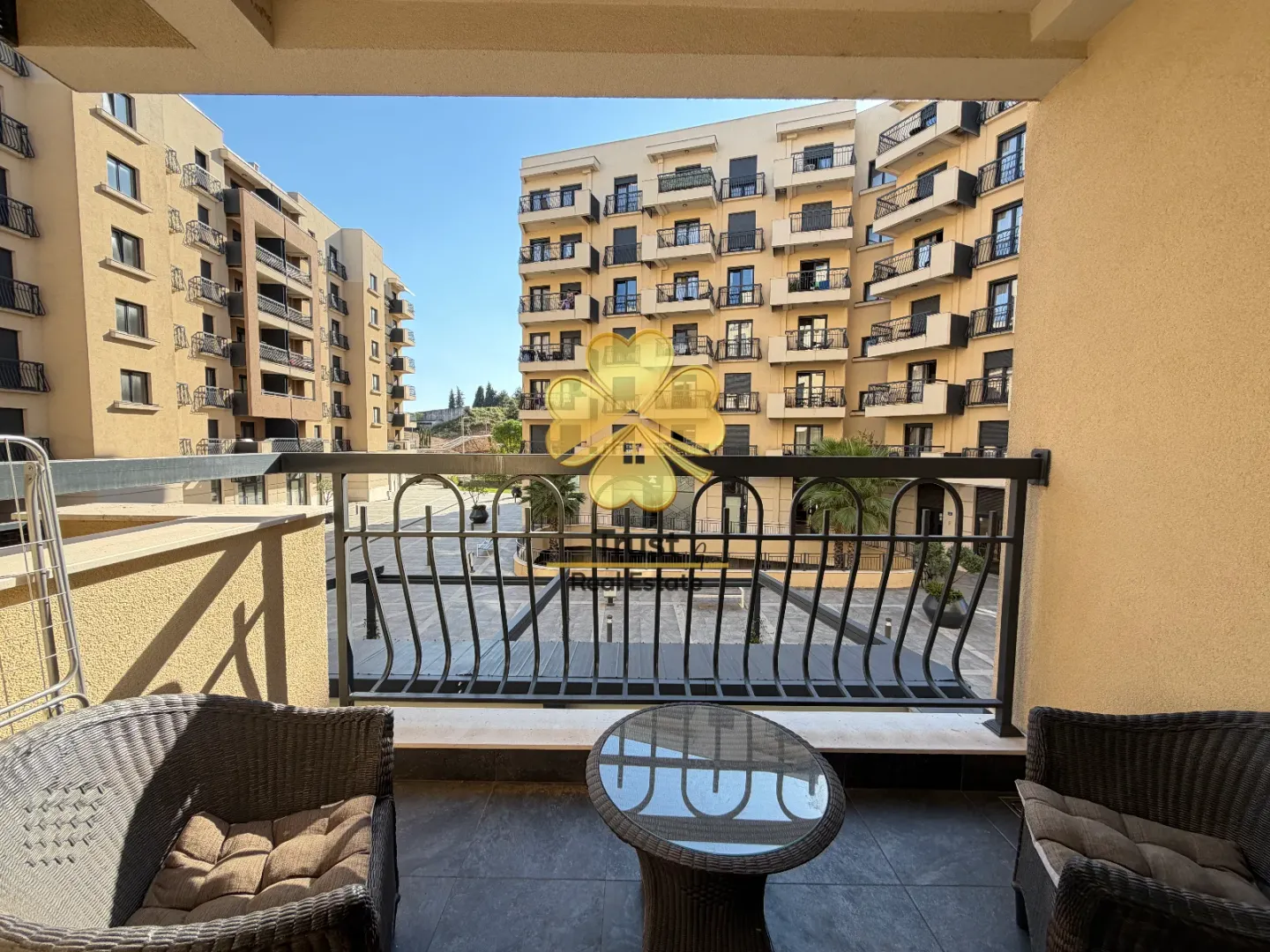 Furnished balcony with seating and a view of surrounding buildings.