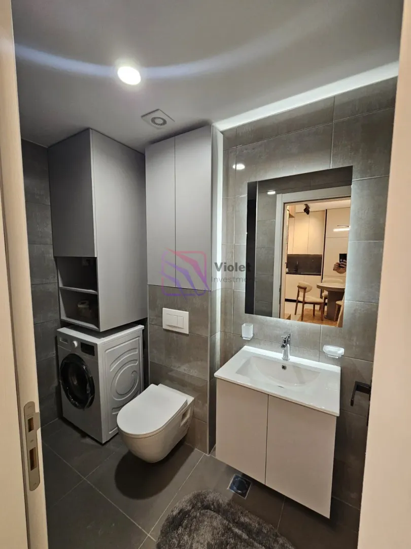 Modern bathroom with a washbasin, toilet, fitted cabinet, and washing machine.