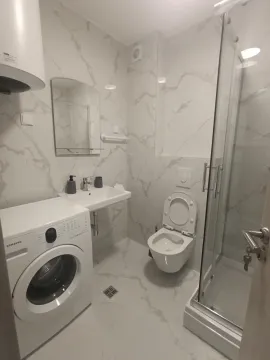 Moderne kupatilo obloženo mermernim pločicama sa tuš kabinom, umivaonikom i veš mašinom. - image 7