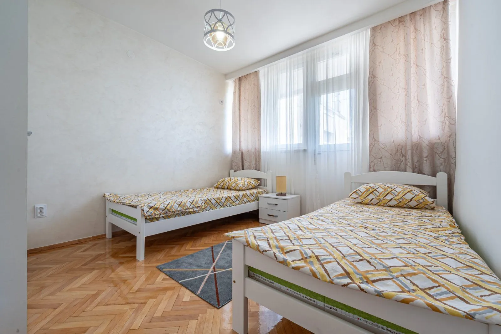 A bedroom with two single beds and parquet flooring.