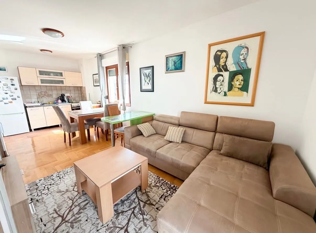 Living room with sofa, dining area, and kitchen in the background.