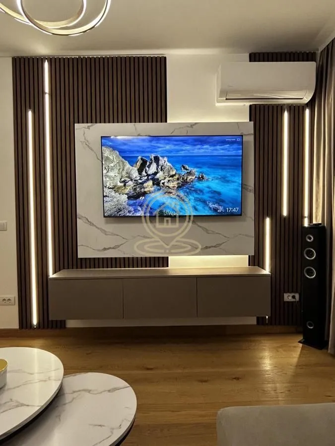 Living room with TV, modern wood paneling, and decorative lighting.