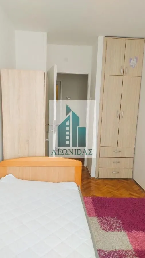 Children's bedroom with a bed, wooden wardrobes, and laminate flooring.