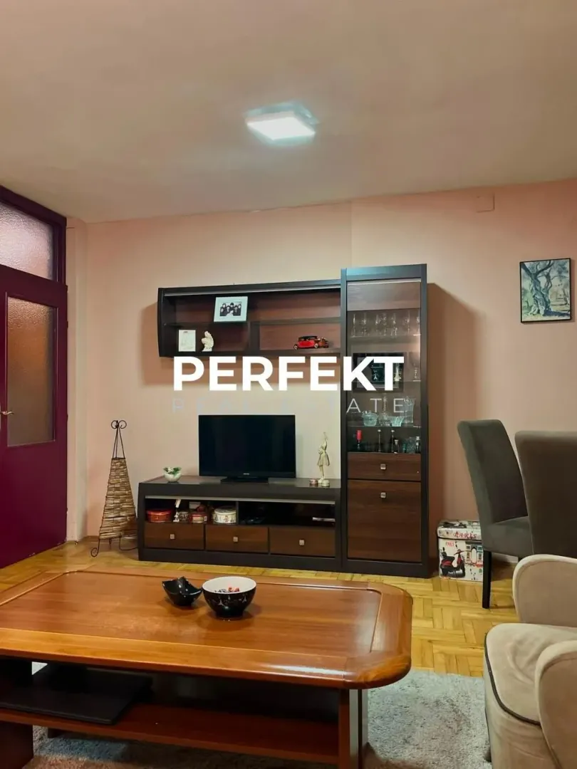 Dnevni boravak sa garniturom, TV komodom i drvenim stočićem.