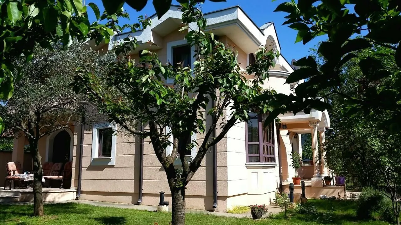 Two-story family house with a landscaped yard and greenery.