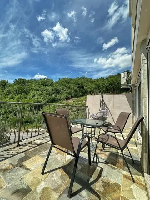 Spacious terrace with patio furniture and a view of greenery.
