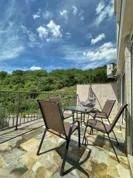 Spacious terrace with patio furniture and a view of greenery. - image 11