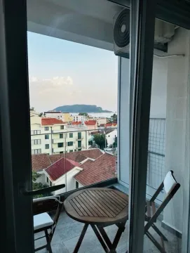 Smaller furnished balcony with a table and two chairs and a view of the city and sea. - image 6