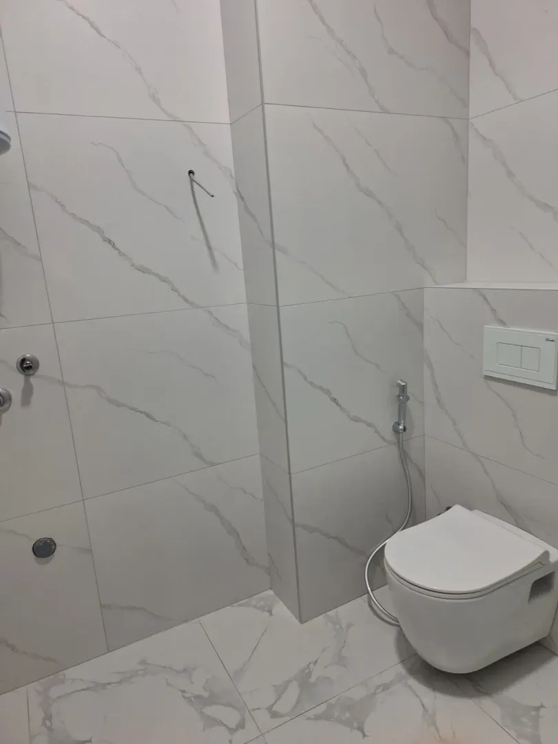 Moderno opremljeno kupatilo sa bijelim keramičkim pločicama i sanitarijama.