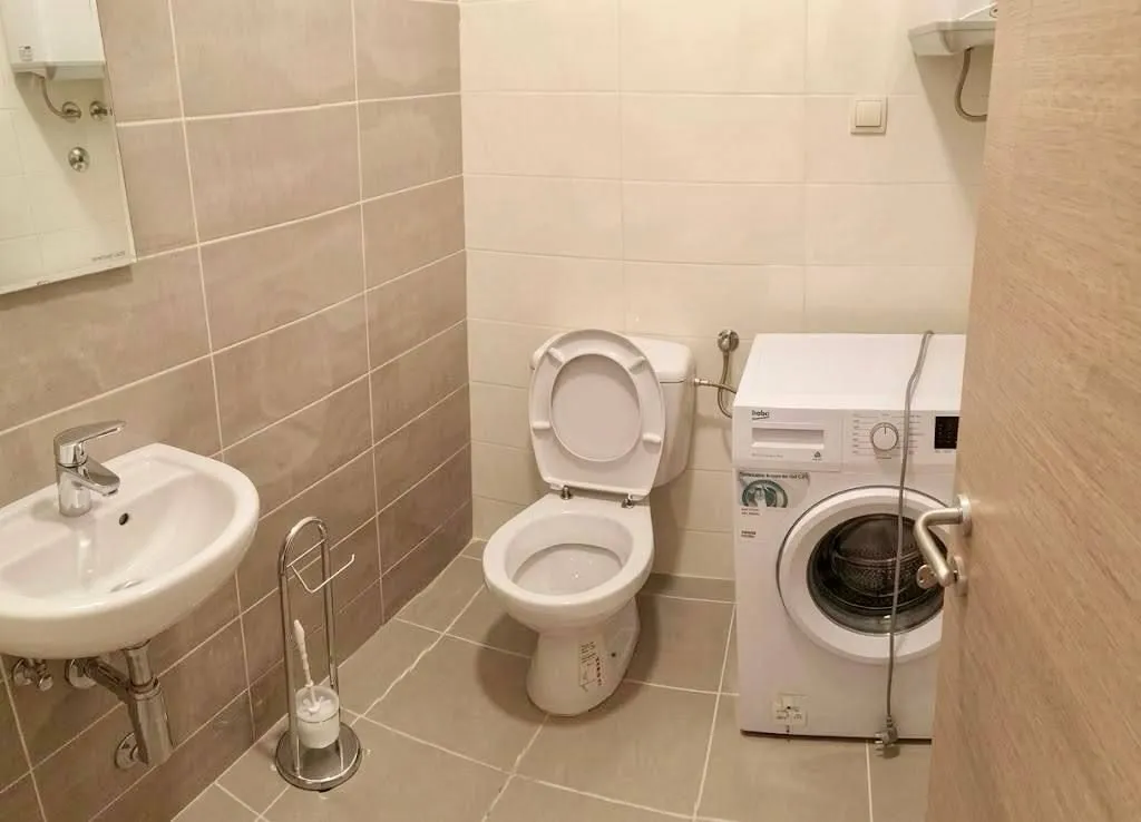 Manje kupatilo sa umivaonikom, WC šoljom i veš mašinom.
