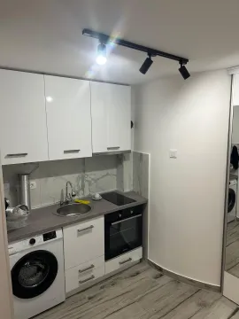 Small white kitchen with a sink, built-in oven, and washing machine. - image 5