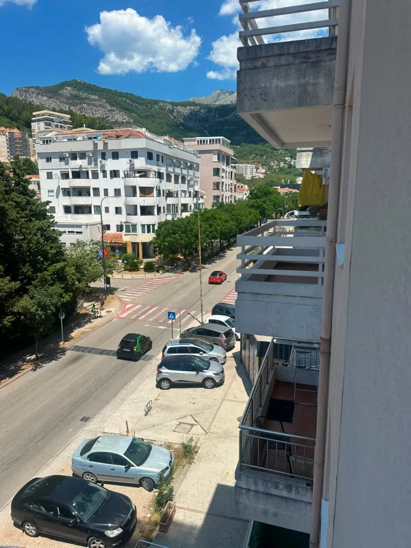 Pogled sa terase na ulicu, okolne zgrade i planine.