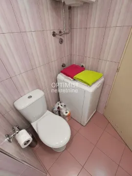 Manje kupatilo sa wc šoljom, veš mašinom i pločicama na zidovima. - image 19