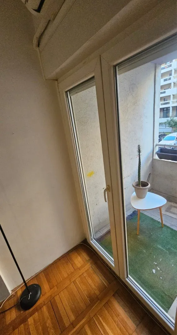 Manji balkon sa stolom i saksijom sa biljkom.
