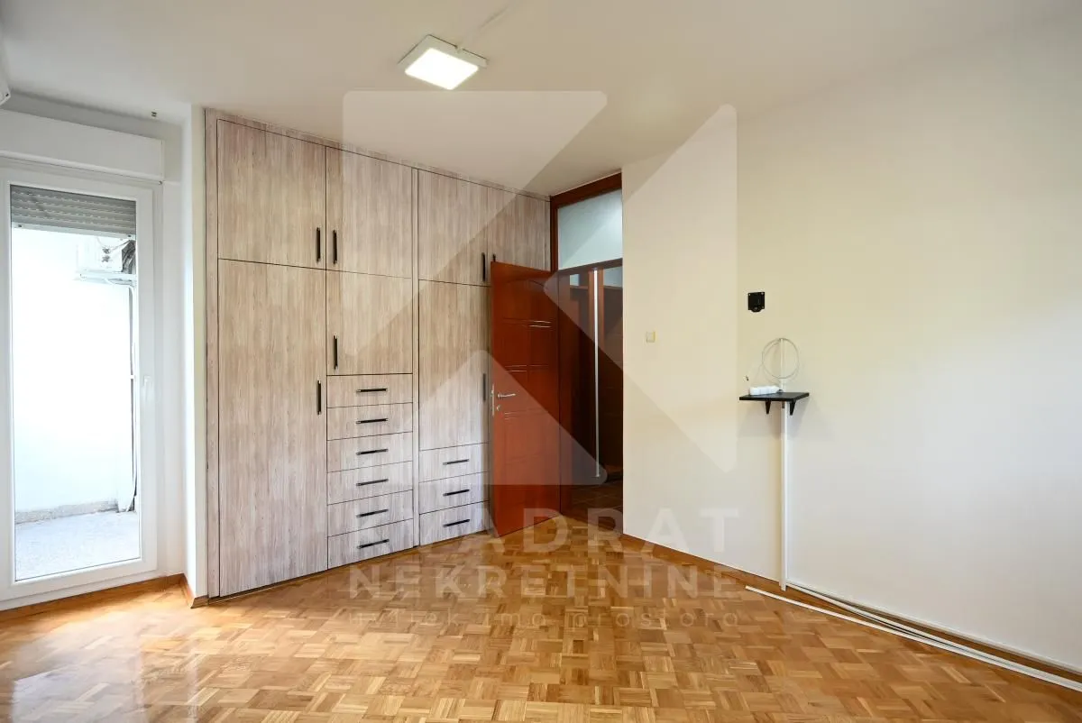 Empty bedroom with a built-in wardrobe and parquet flooring.