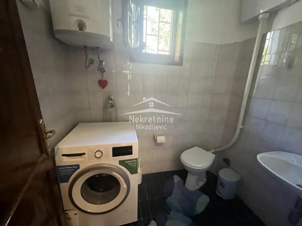 Bathroom with a washing machine, toilet, and a small sink.