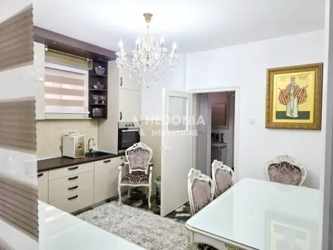 Kuhinja sa trpezarijom opremljena klasičnim nameštajem i lusterom. - image 2