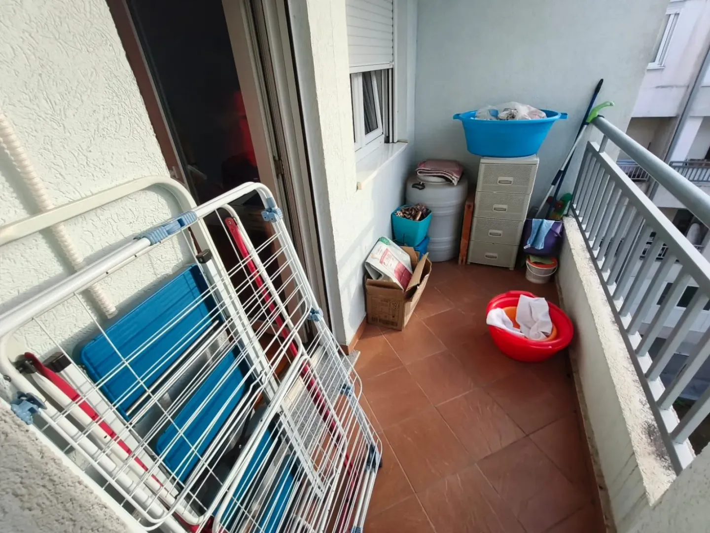 Manji balkon sa sušačem za veš i različitim kućnim potrepštinama.