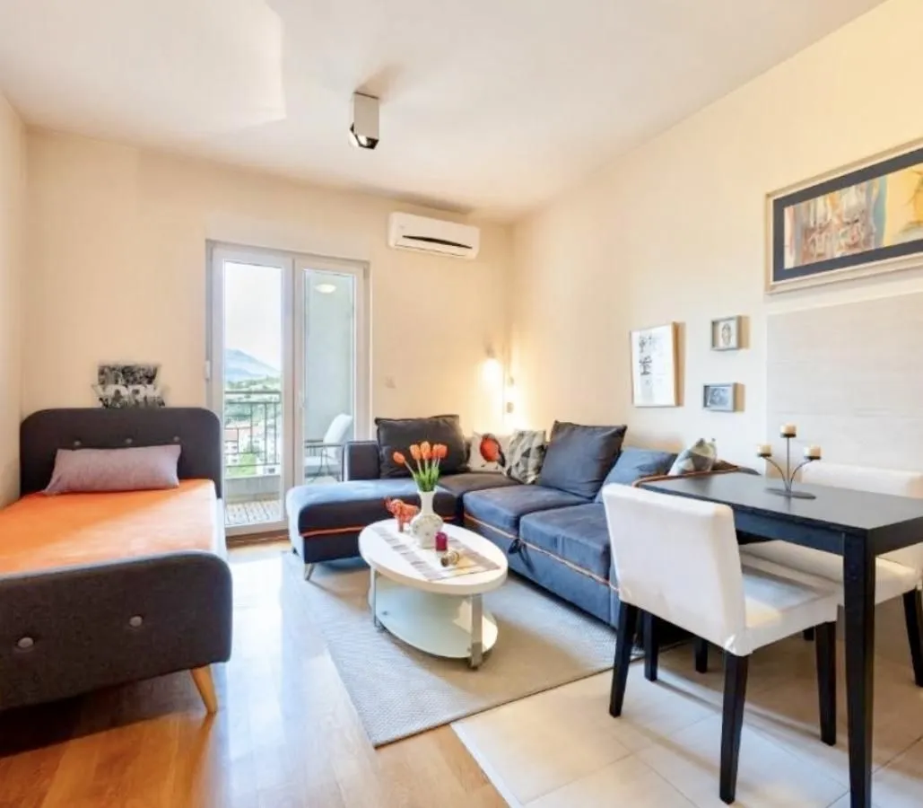 Living room with a sofa set, dining table, and balcony access.