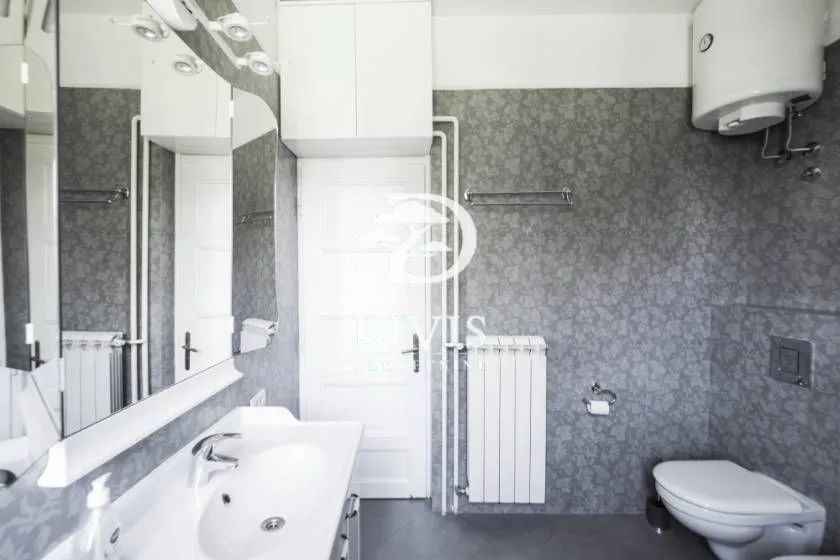 Bathroom with sink, mirror, toilet, and water heater.
