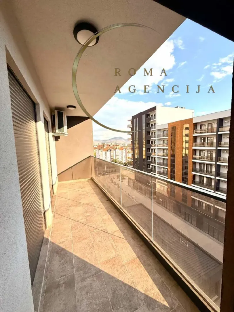 Spacious balcony with a glass railing and city view.