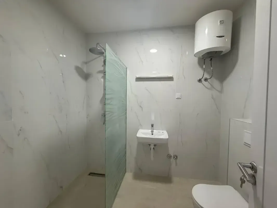 Savremeno opremljeno kupatilo sa tuš kabinom, umivaonikom, toaletom i bojlerom.