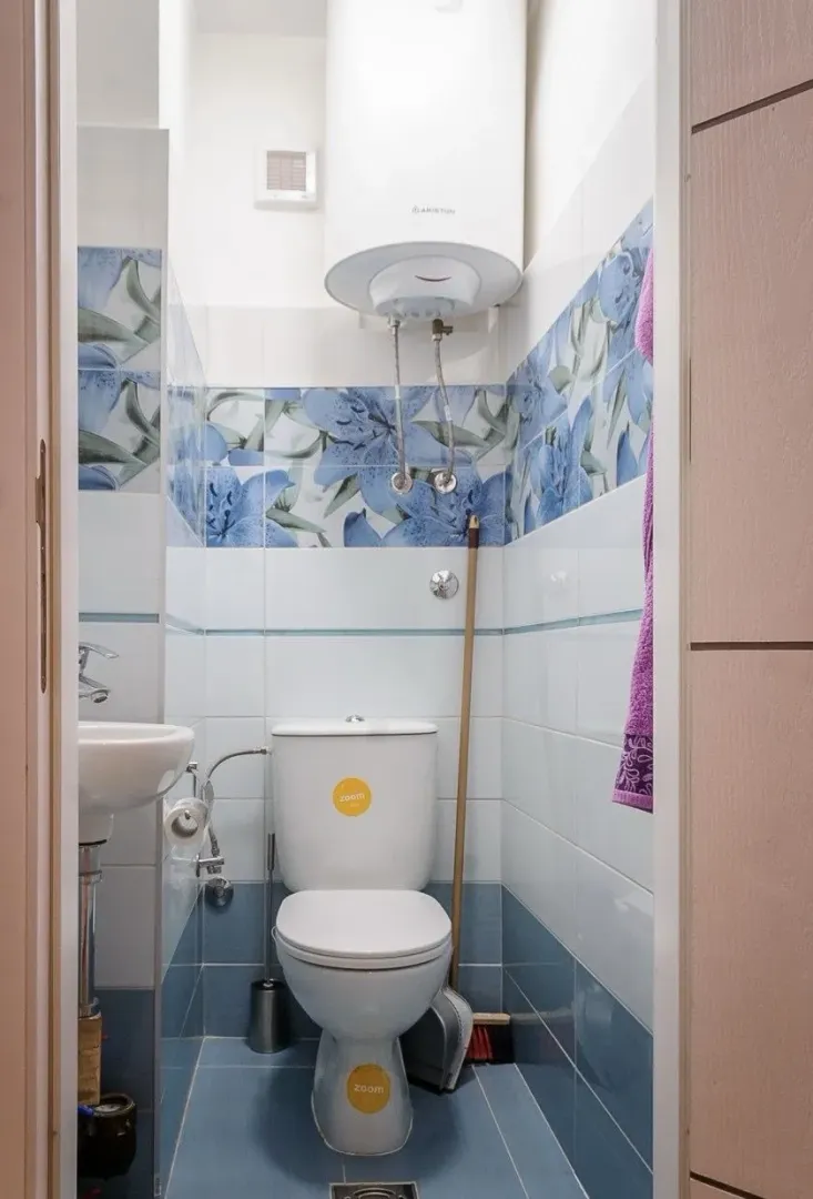 Small bathroom with a toilet, sink, and water heater.