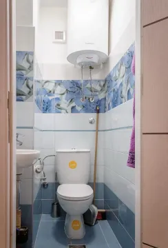 Small bathroom with a toilet, sink, and water heater. - image 10