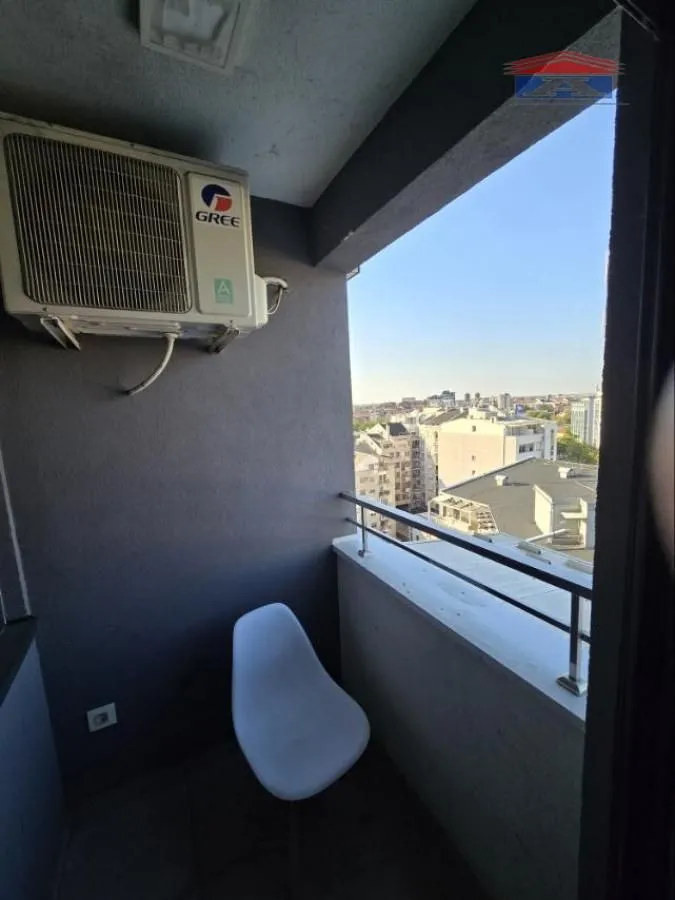Manji balkon sa stolicom i klima uređajem, sa pogledom na grad.