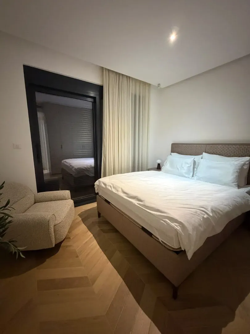 Modern bedroom with a double bed, armchair, and access to the terrace.