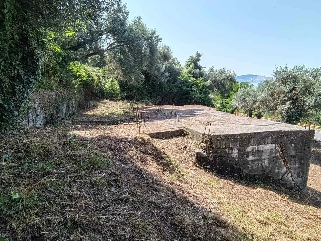 Betonska ploča i temelj na placu okruženom zelenilom.