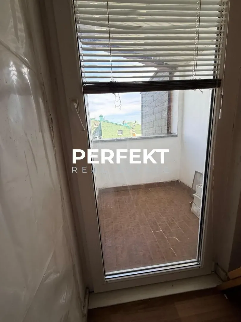 Pogled na manji popločani balkon sa vrata u zatvorenom prostoru.