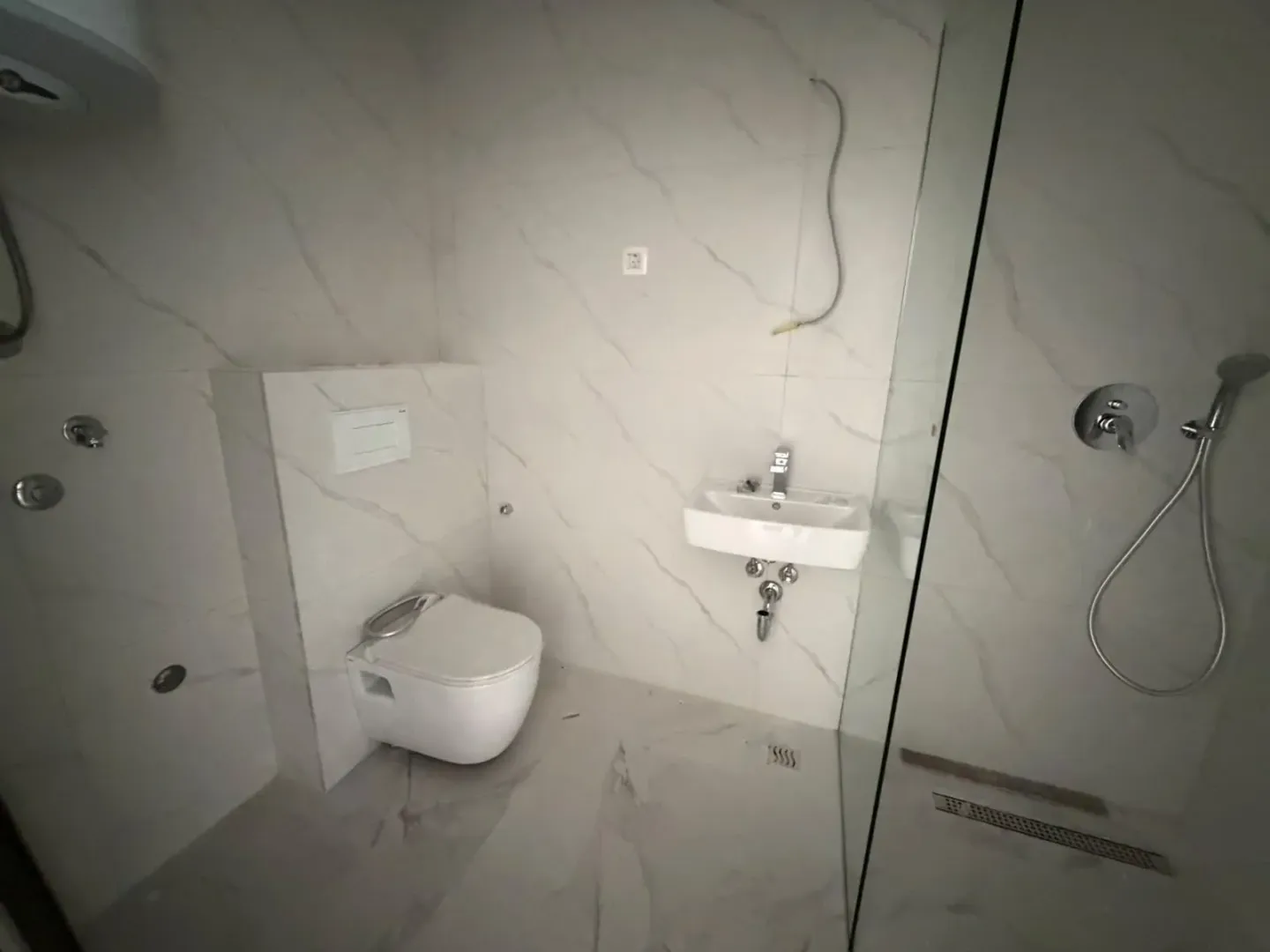 Novoopremljeno kupatilo sa tuš kabinom i bijelim sanitarijama.