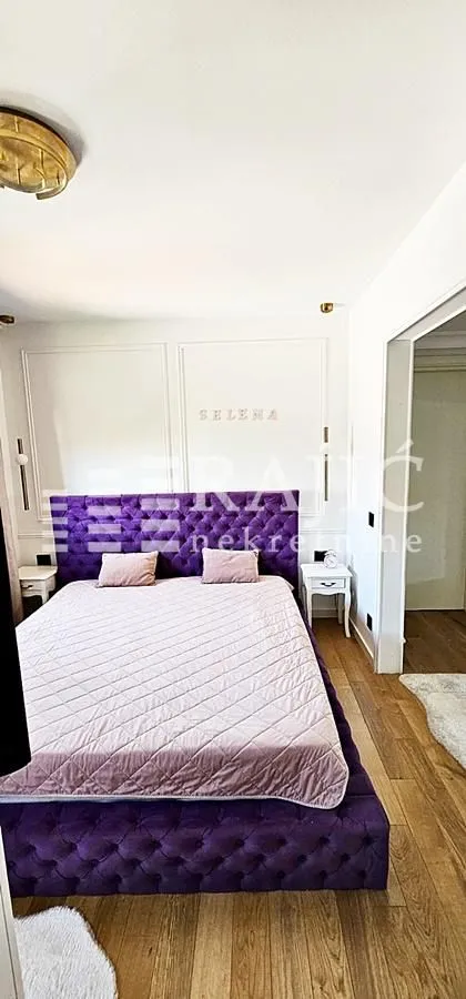 Bedroom with a large purple bed and white nightstands.