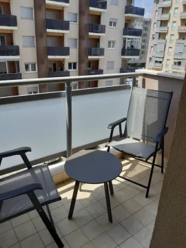 A balcony with two chairs and a small table, overlooking neighboring buildings. - image 15