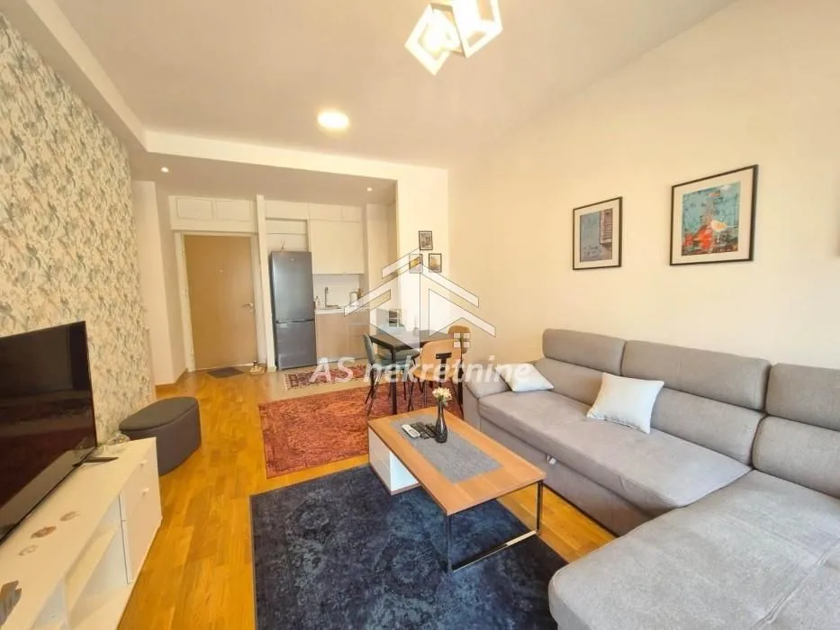 Living room with a sofa, TV unit and dining area in the background.