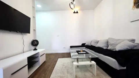 Modern living room with a sofa, TV, and glass coffee table. - image 3