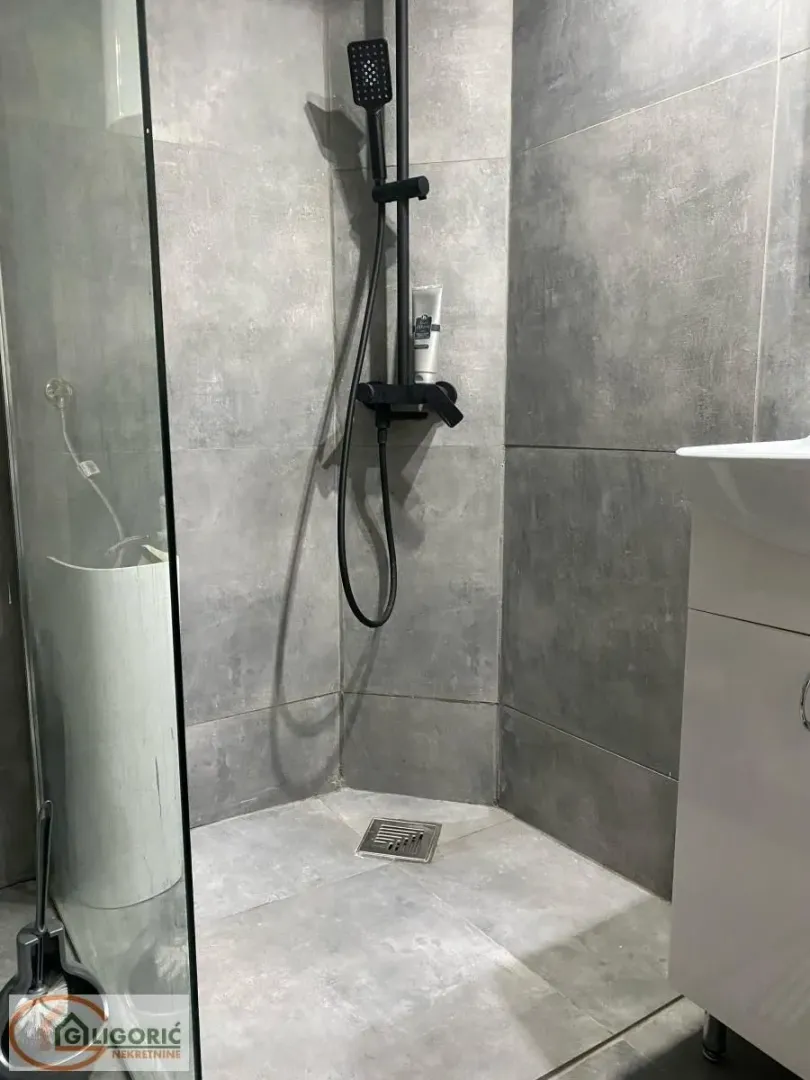 Modernly equipped bathroom with a walk-in shower and grey ceramic tiles.